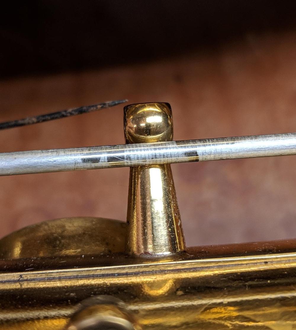 Visible wear on a hinge rod held in front of its post. The shiny bits are where the key was contacting and wearing it smooth over time.